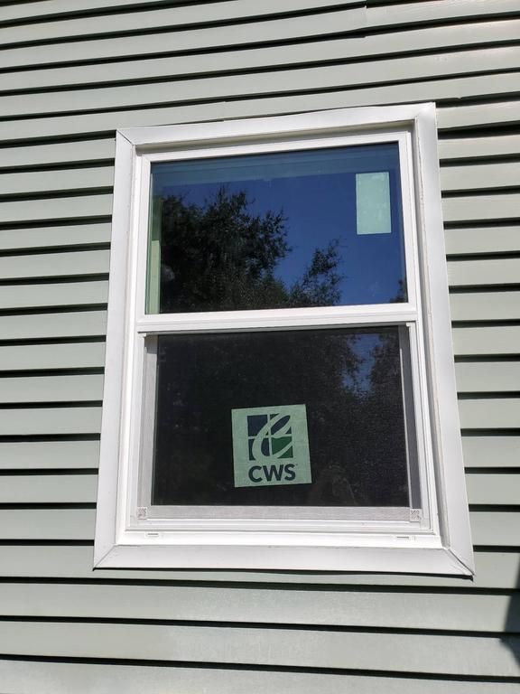 A white-framed window on a house with siding