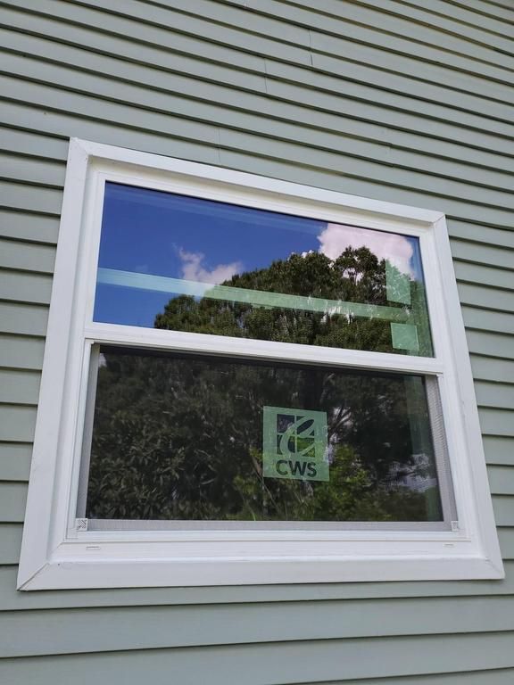 White-framed double-hung window on reflecting sky and trees