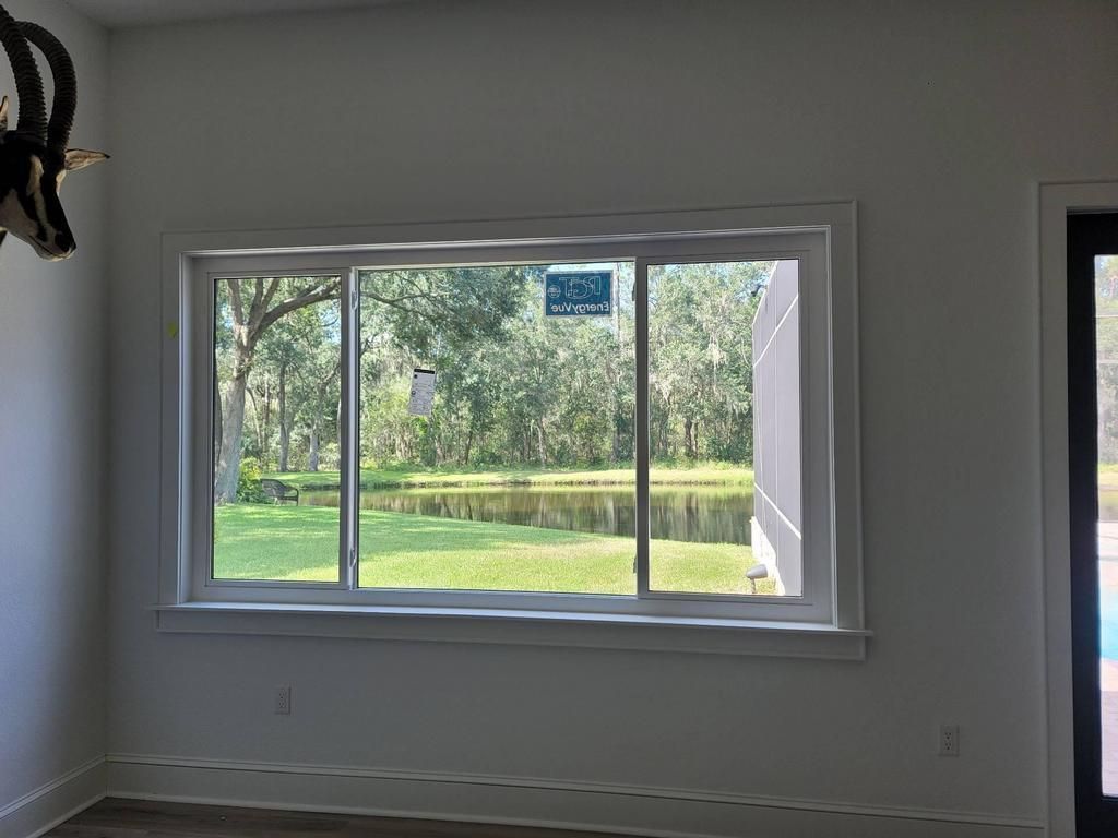Empty room with a large window overlooking a green lawn and trees