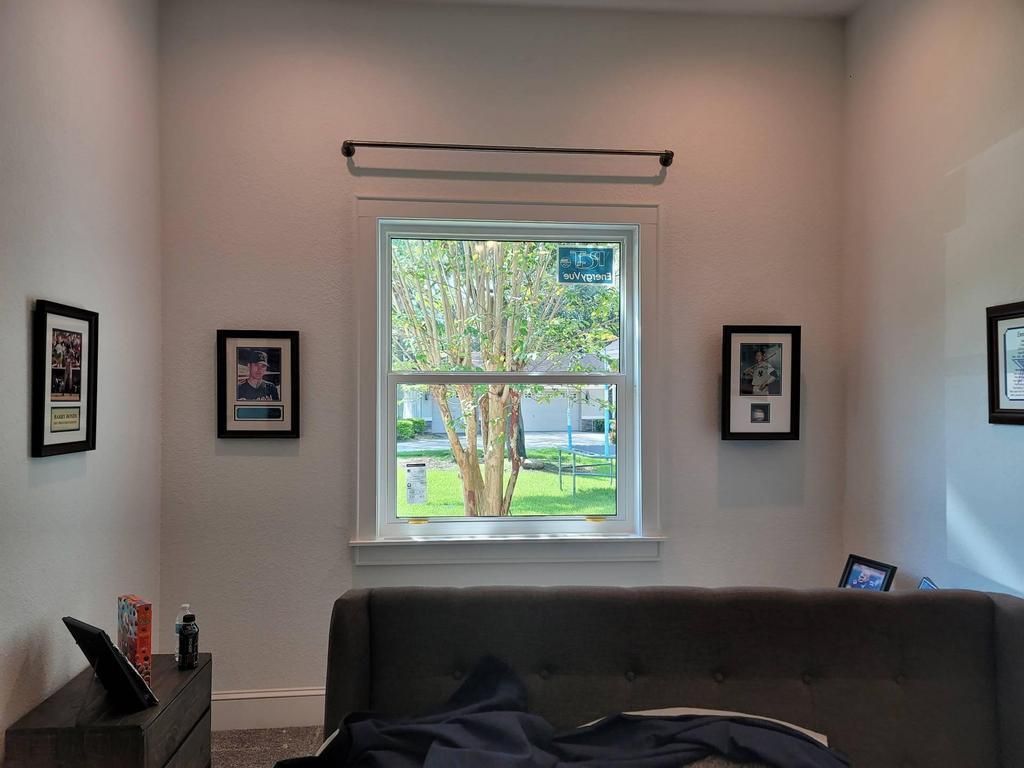 Living room with gray couch, framed wall art, and a window looking out to a green yard