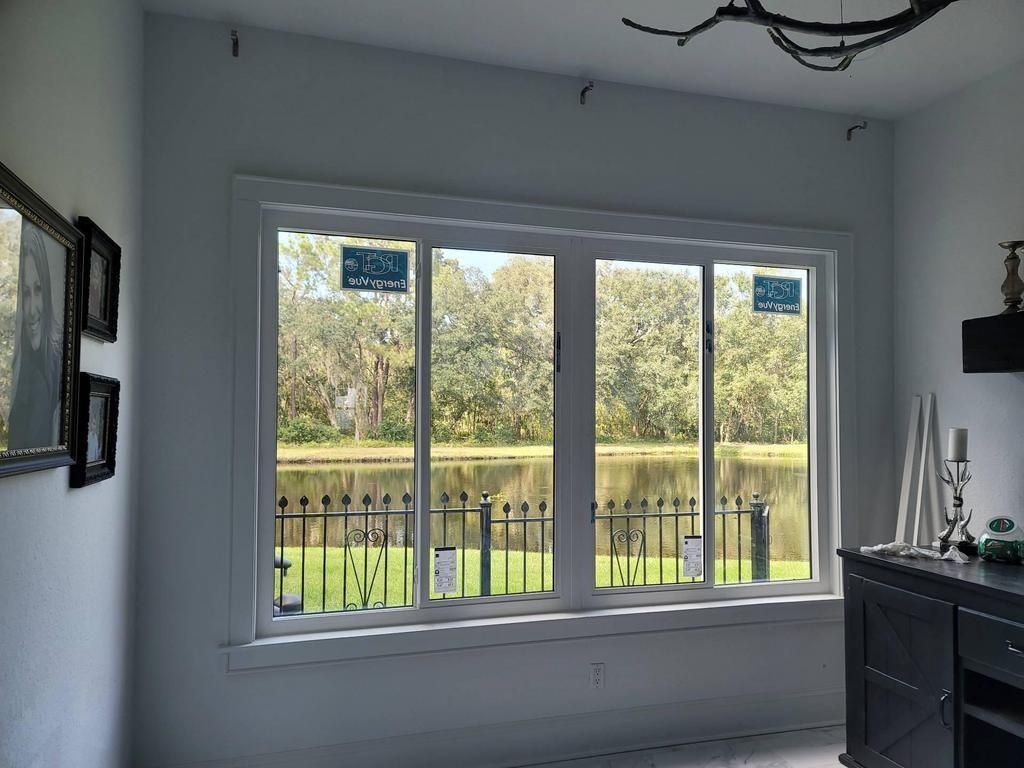 White room with a large window overlooking a river and trees