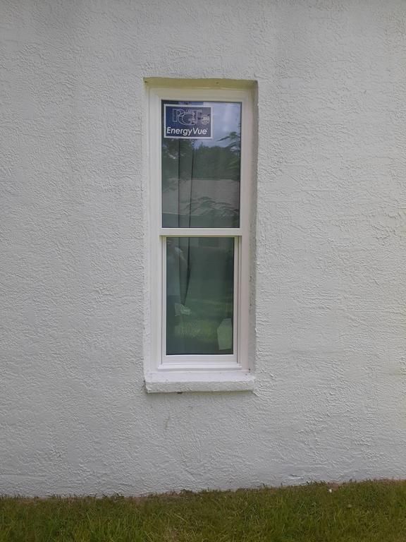 White exterior wall with a narrow vertical window and a strip of grass below