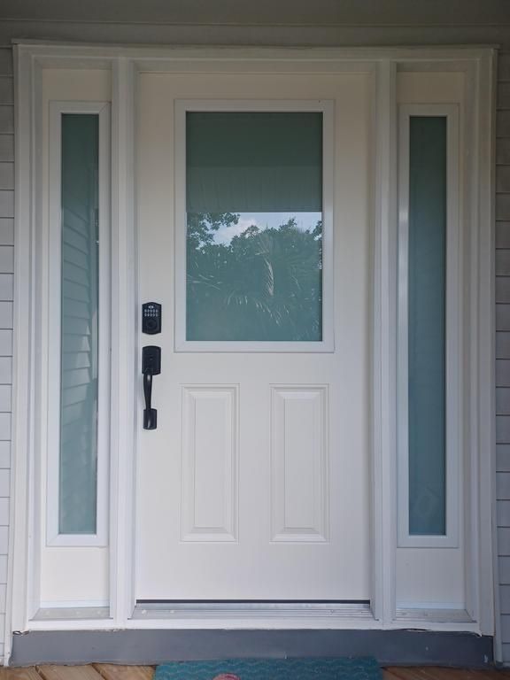 White front door with frosted glass sidelights and a black keypad lock
