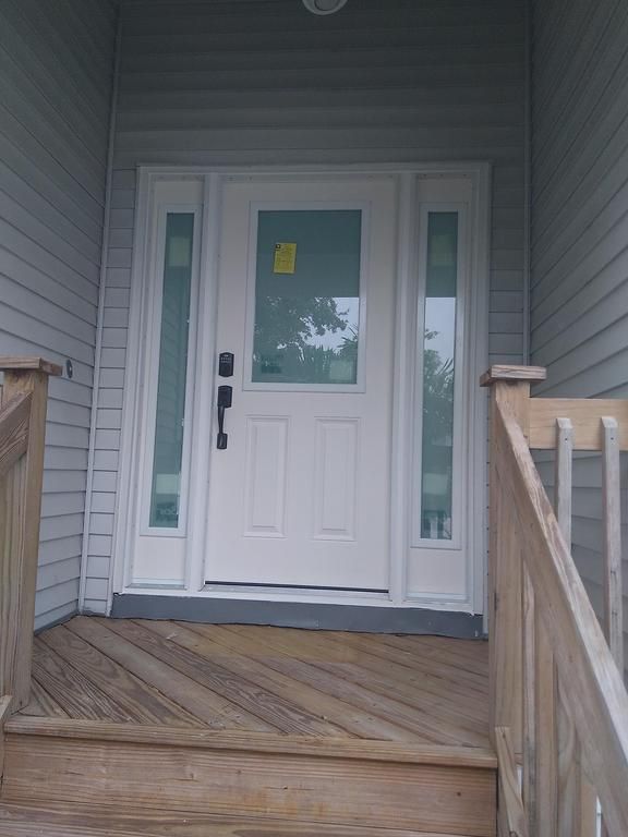 White front door with glass panels and wooden porch steps at a house entrance