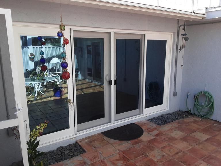 Patio with white sliding glass doors, terracotta tile floor, and a coiled green hose on the wall