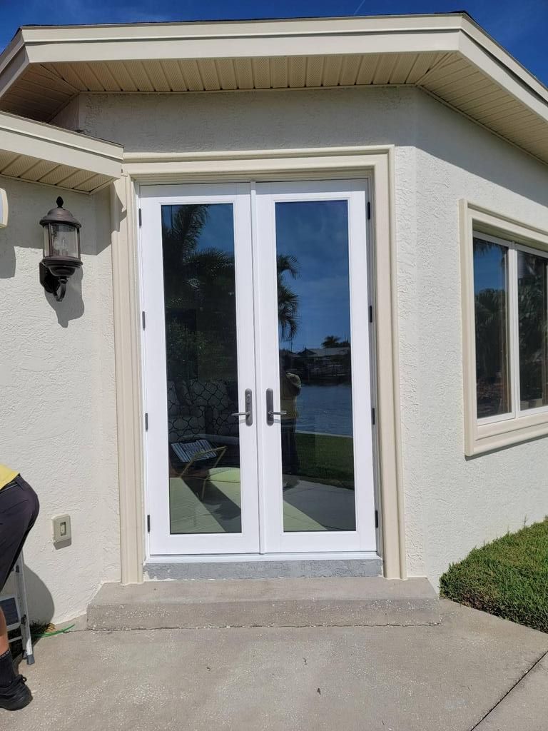 White double glass front door with side windows on a stucco home entrance