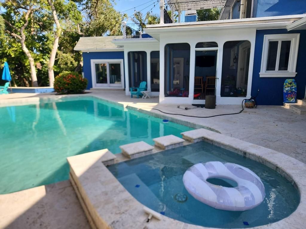 Blue house with glass doors and windows and a backyard pool