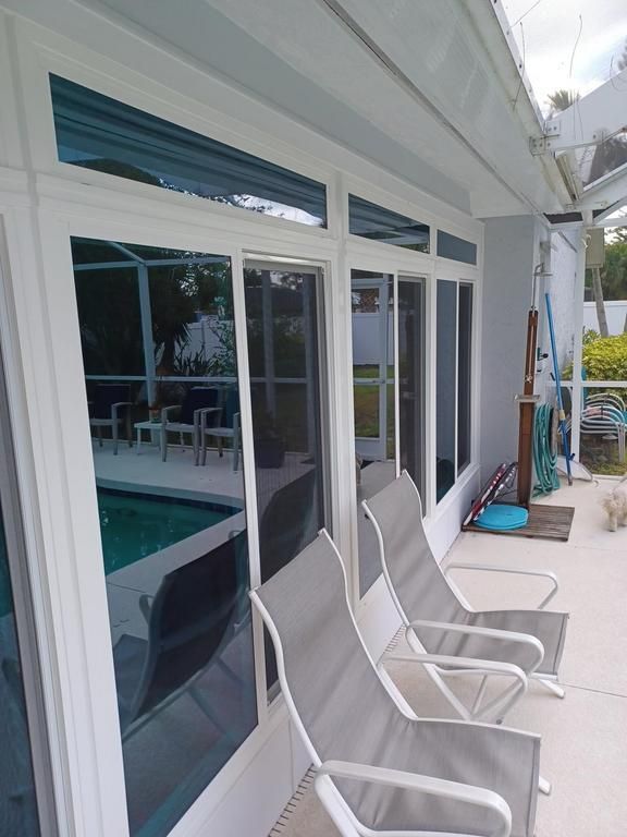 Sliding glass doors beside a patio with pool chairs