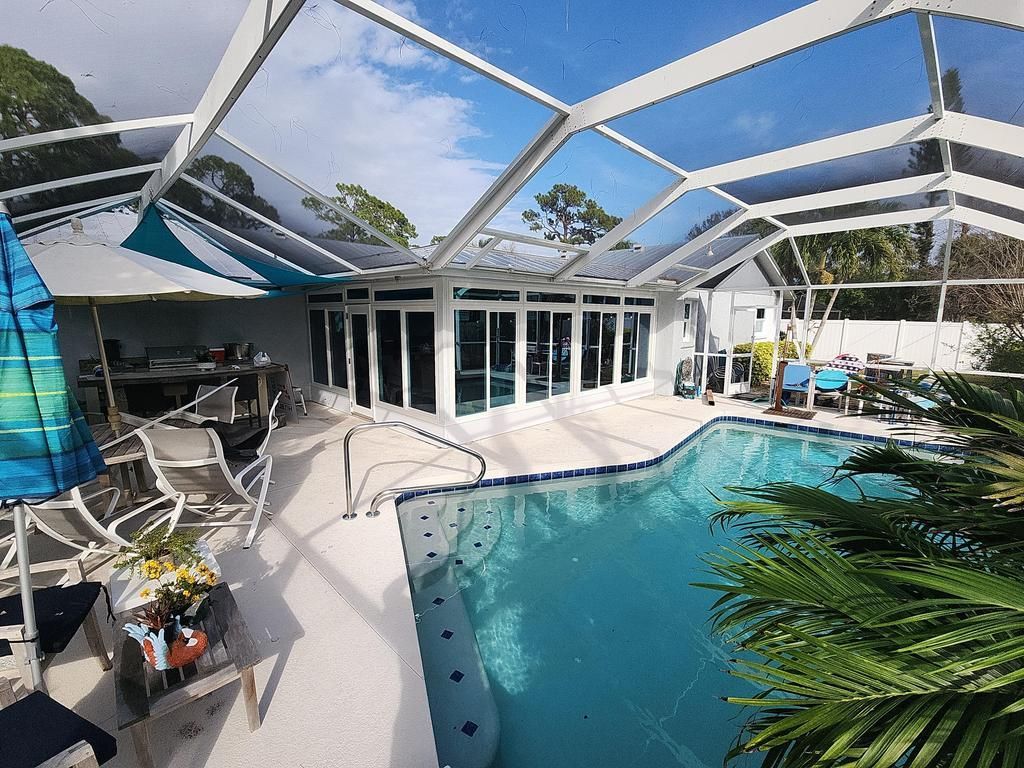 Screened patio with blue pool and white-framed doors and windows
