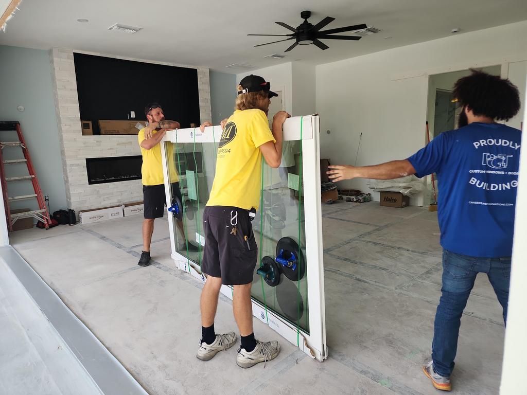 Three workers moving a glass door in a room