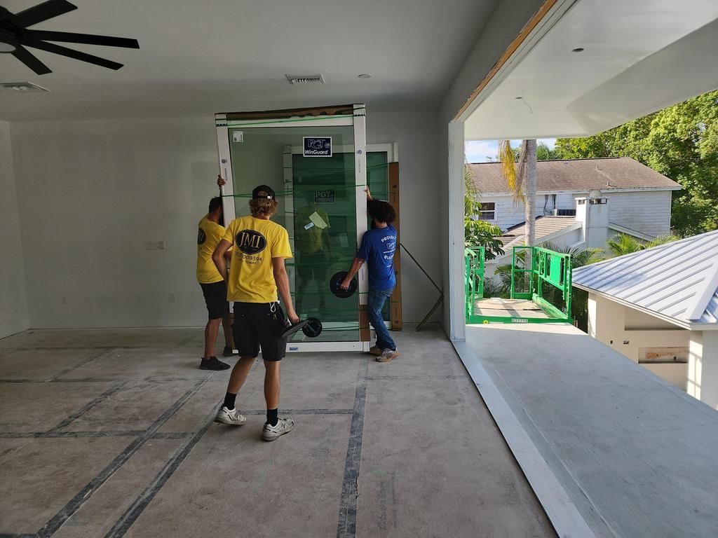 Three people in yellow and blue shirts installing glass panels