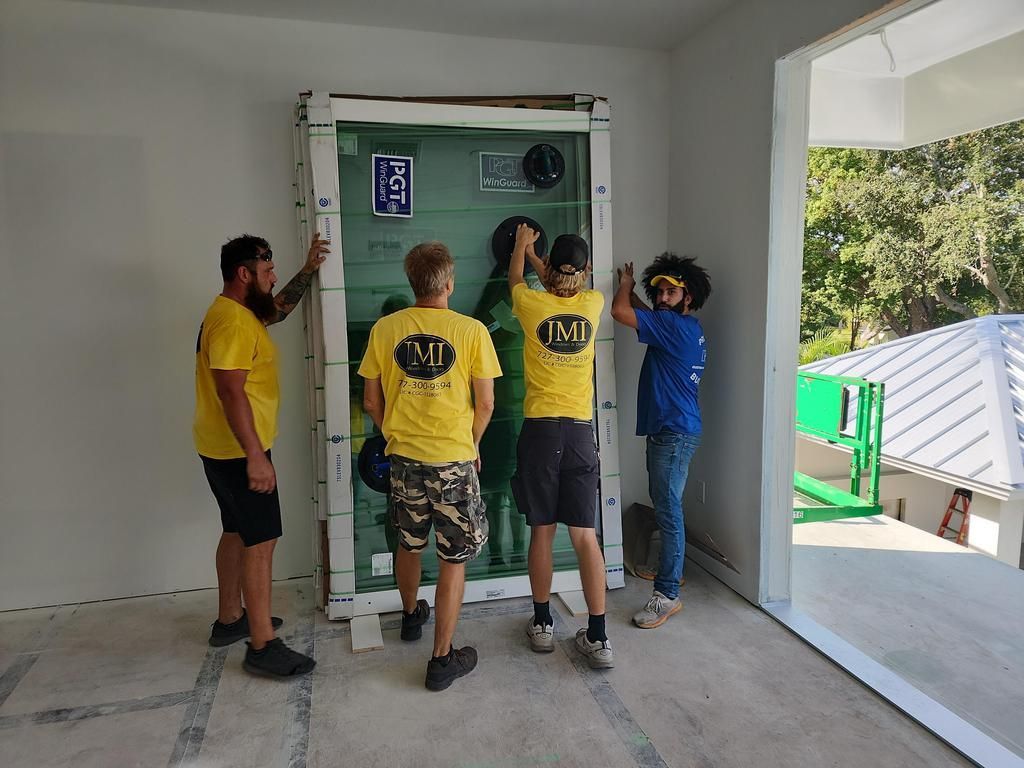 Four workers lifting a large glass panel