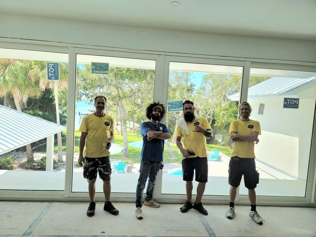 Four people standing indoors in front of large sliding doors