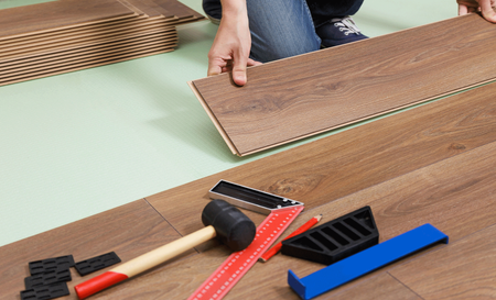 A person is installing a wooden floor with tools on the floor.