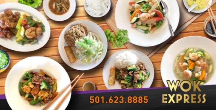 A wooden table topped with plates of food from wok express