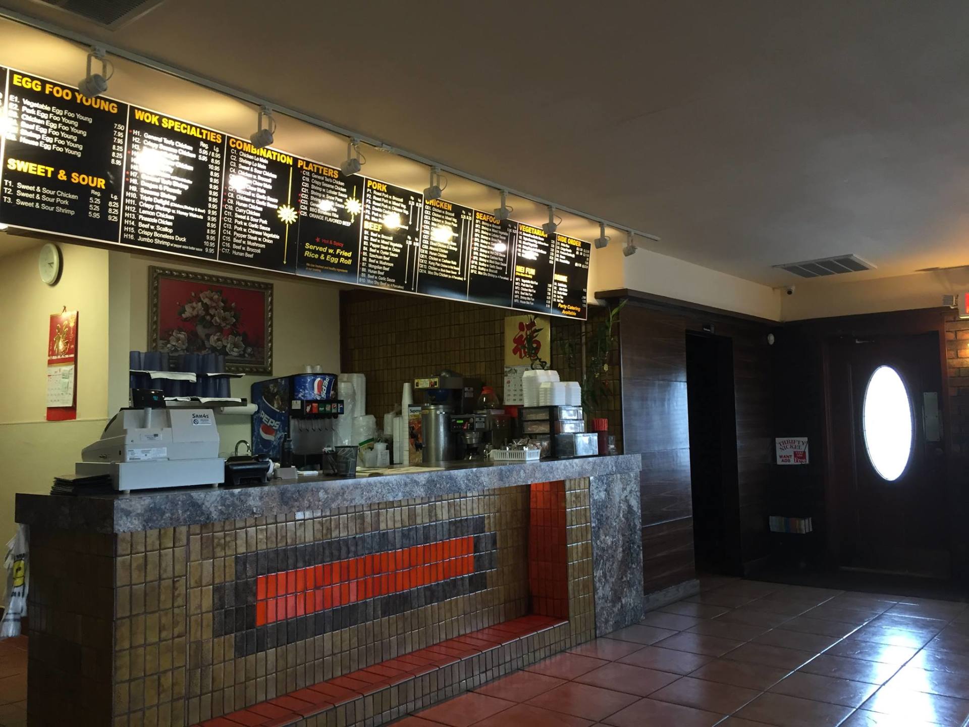 A restaurant with a counter and a menu above it