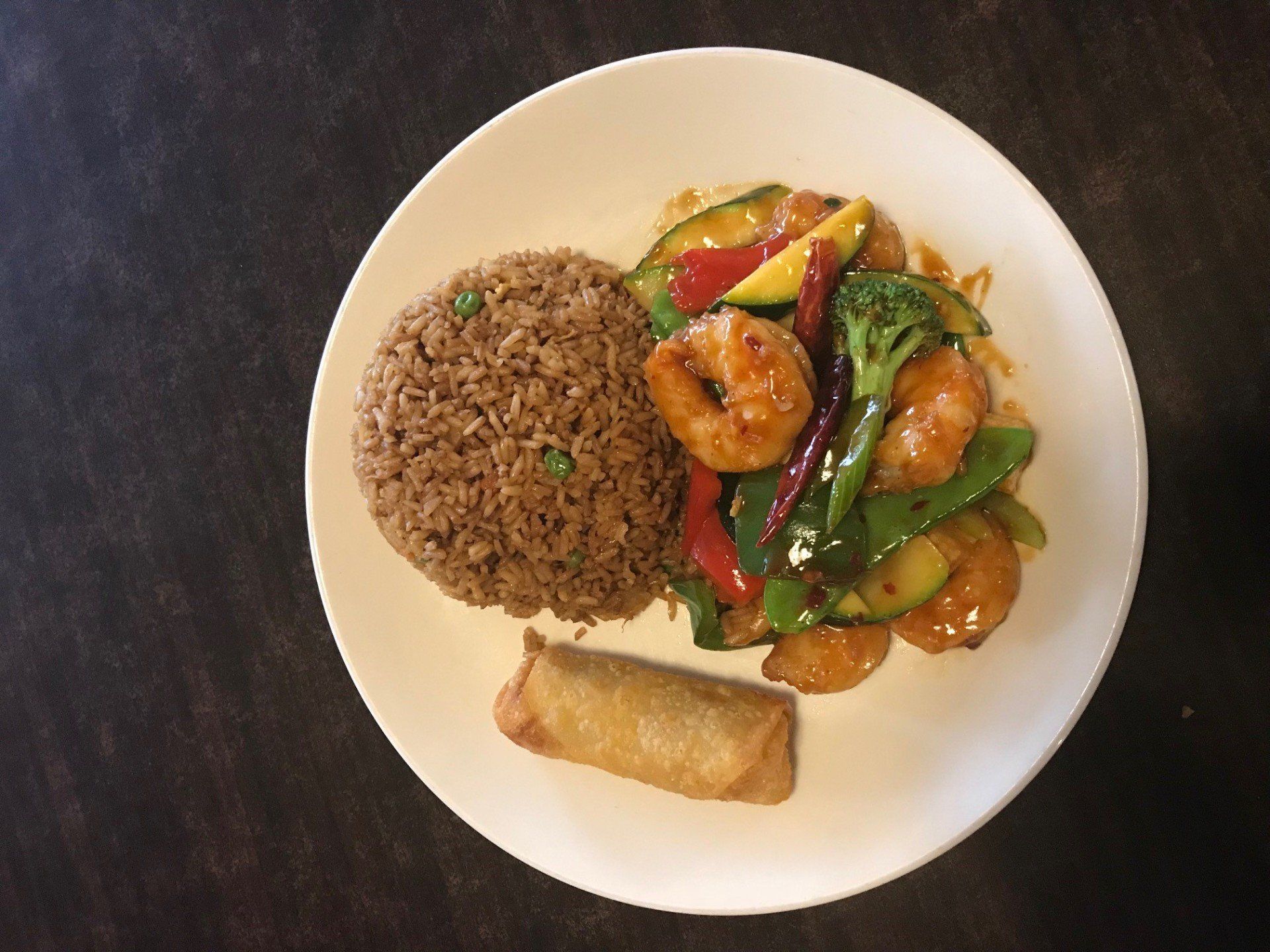 A plate of food with shrimp , rice and vegetables on a table.