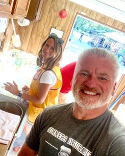 A man and a woman are taking a selfie in a kitchen.