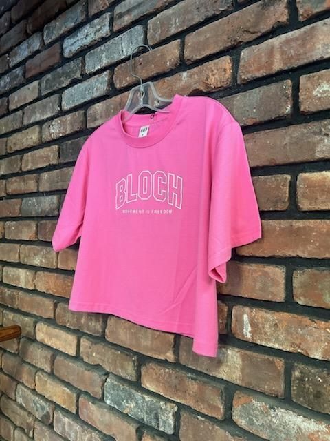 A pink crop top is hanging on a brick wall.