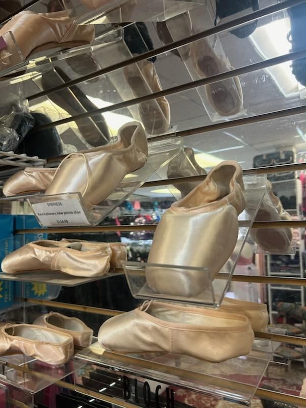 A bunch of pointe shoes are sitting on a shelf in a store.