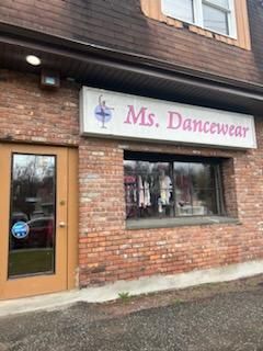 The front of a brick building with a sign that says `` ms. dancewear ''.