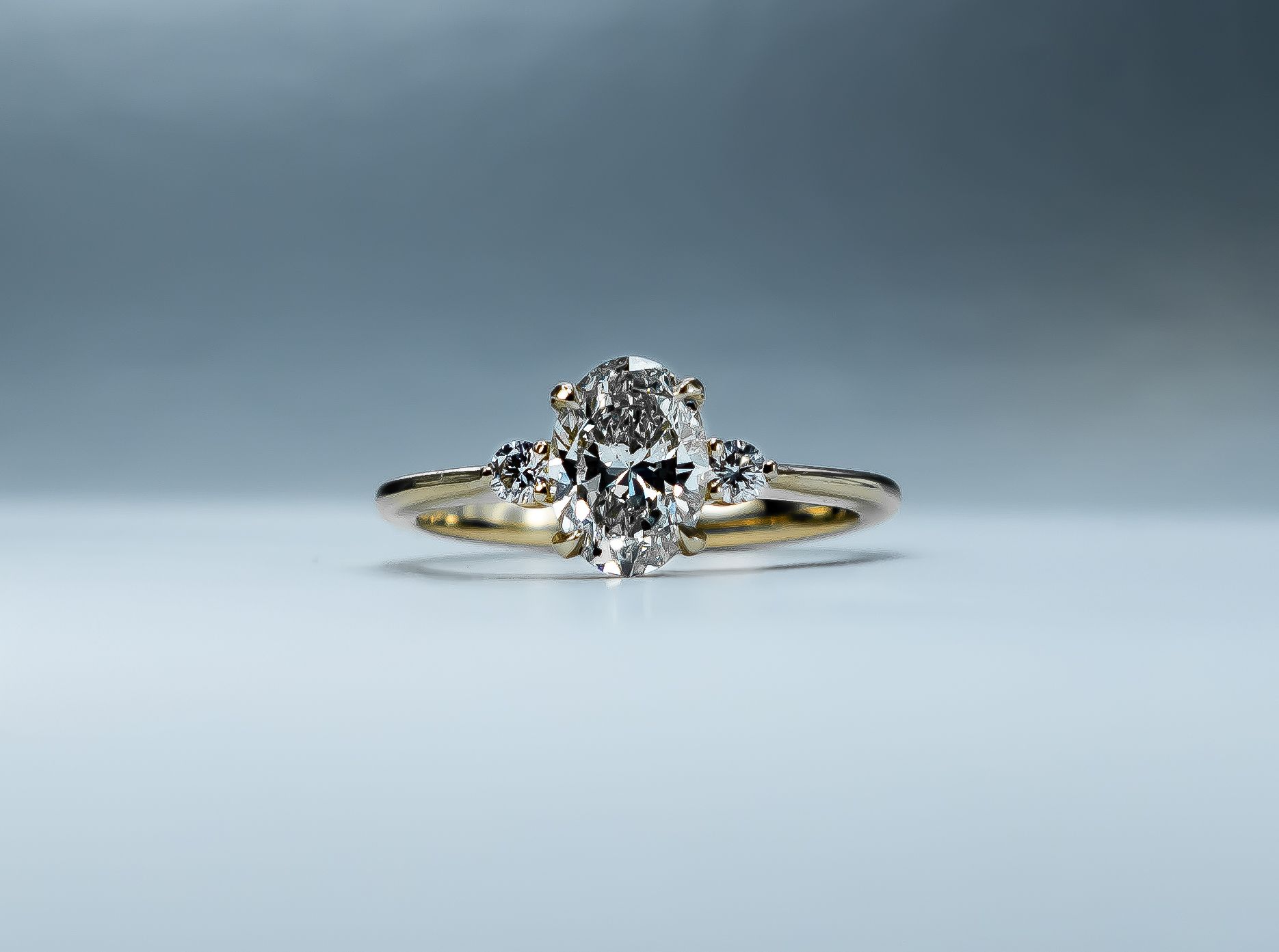 Diamond ring with a gold band on a light gray background