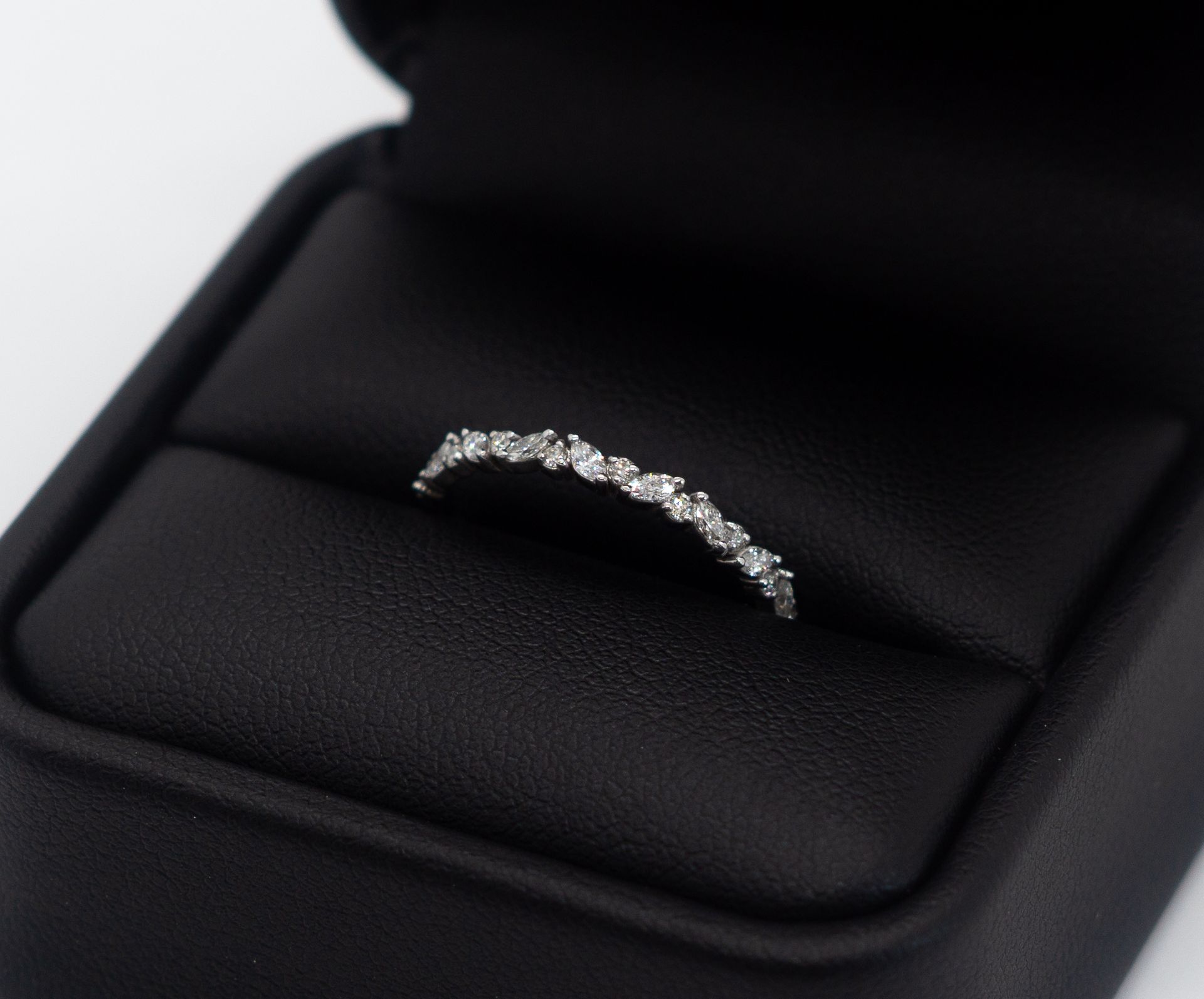Small silver curved ring on a black jewelry display box.