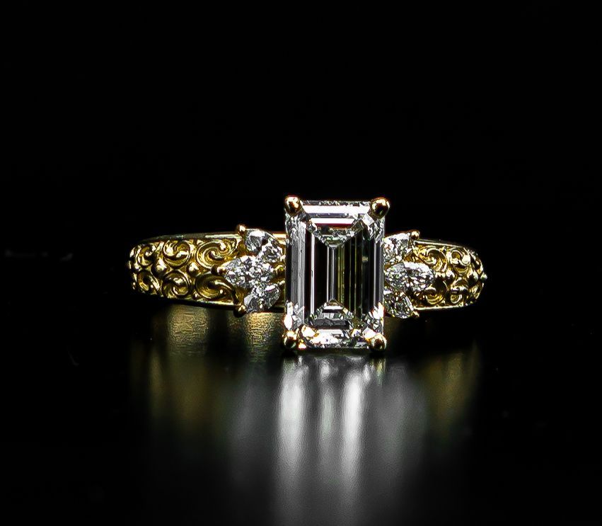 Gold ring with a rectangular diamond center stone on a black background