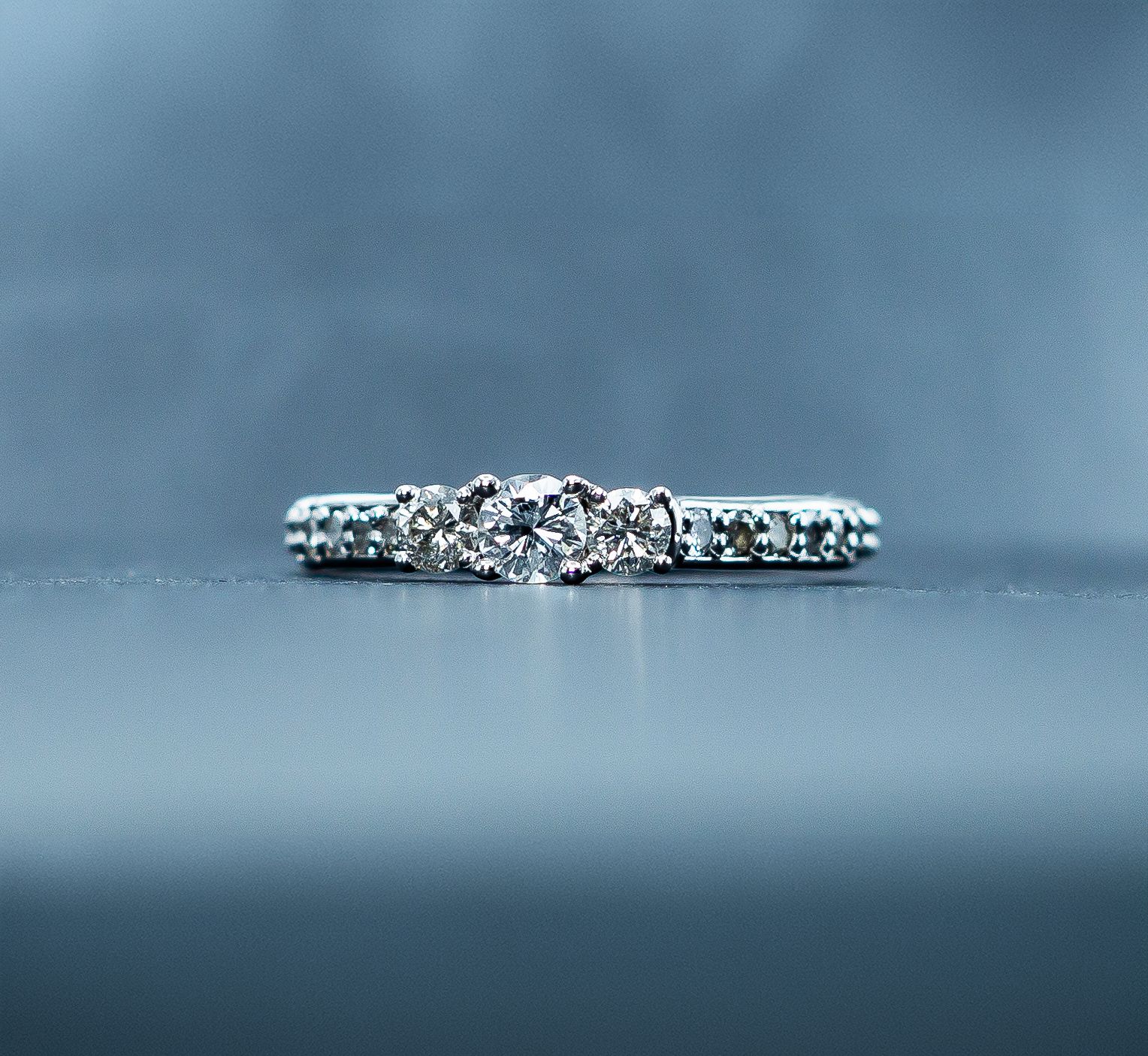 Diamond engagement ring on a blue surface with a blurred blue background