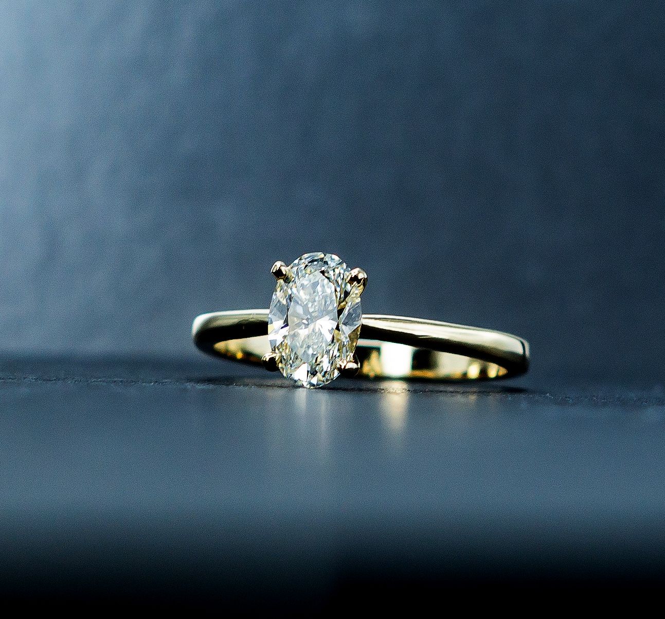 Gold ring with an oval diamond on a dark blue surface