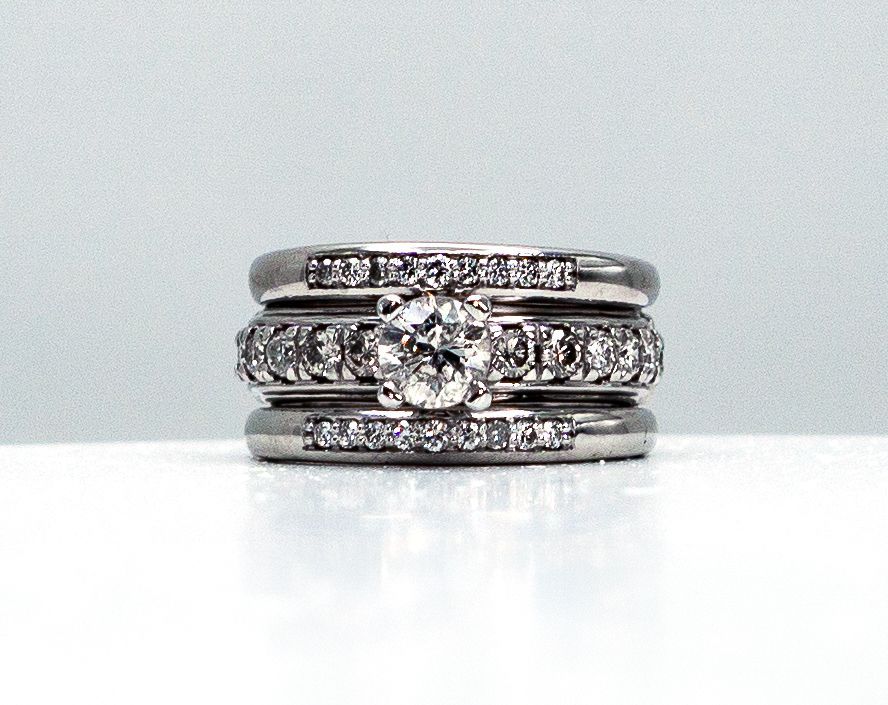 Three silver rings stacked, one with a central diamond and side stones on a white background
