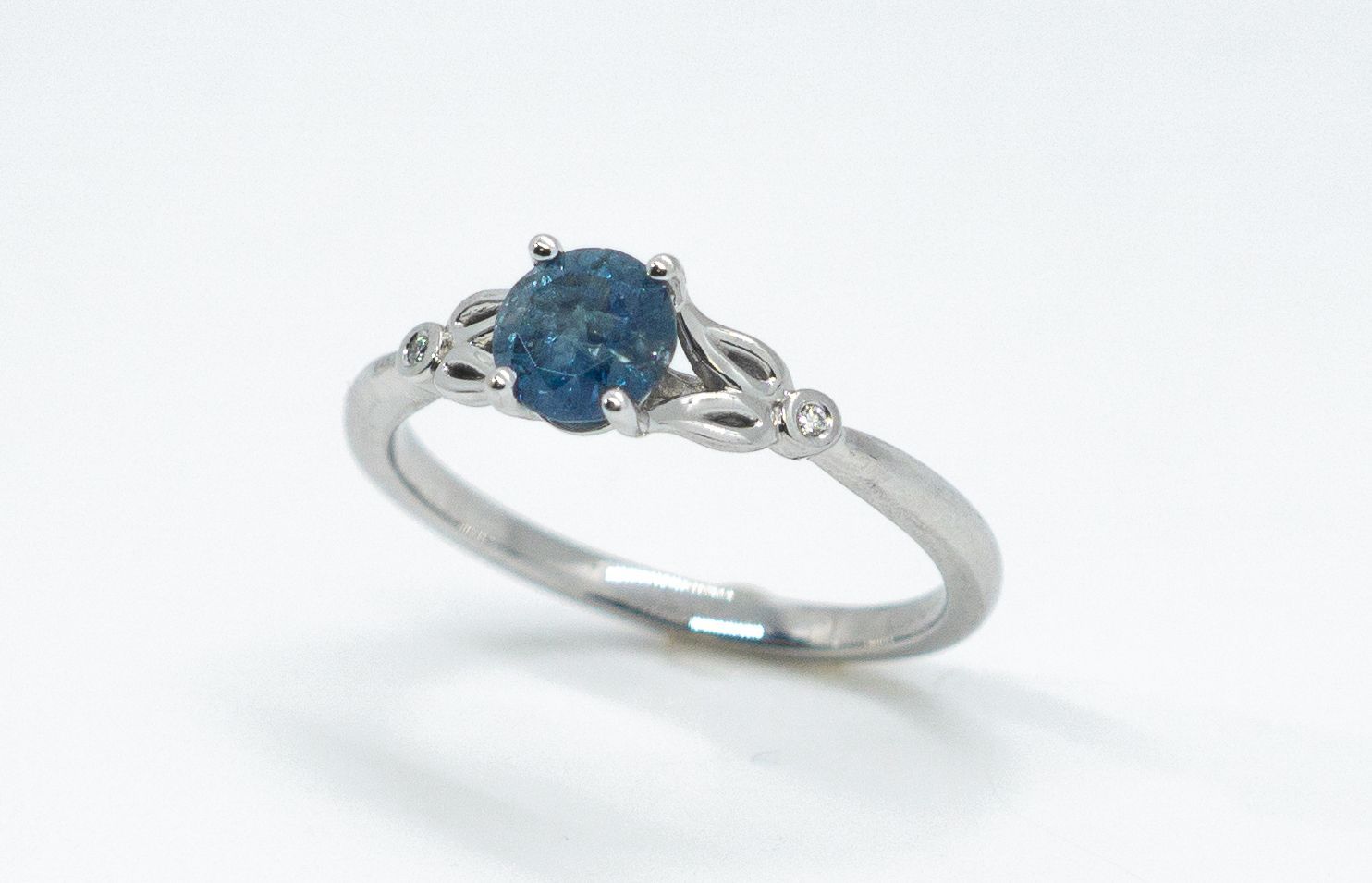 Silver ring with a blue gemstone and delicate swirl design on a white background