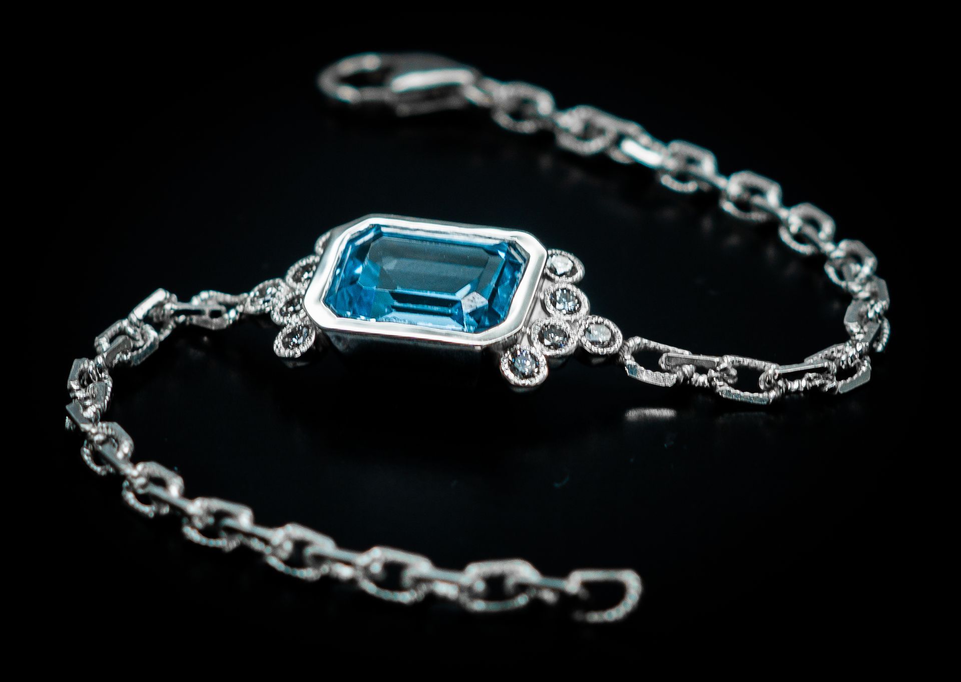 Silver bracelet with a blue rectangular gemstone on a black background