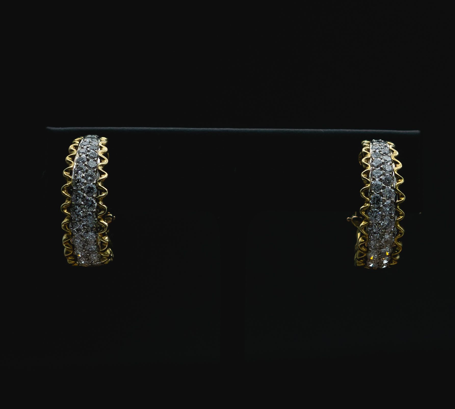 Pair of gold and silver dangling earrings on a black background