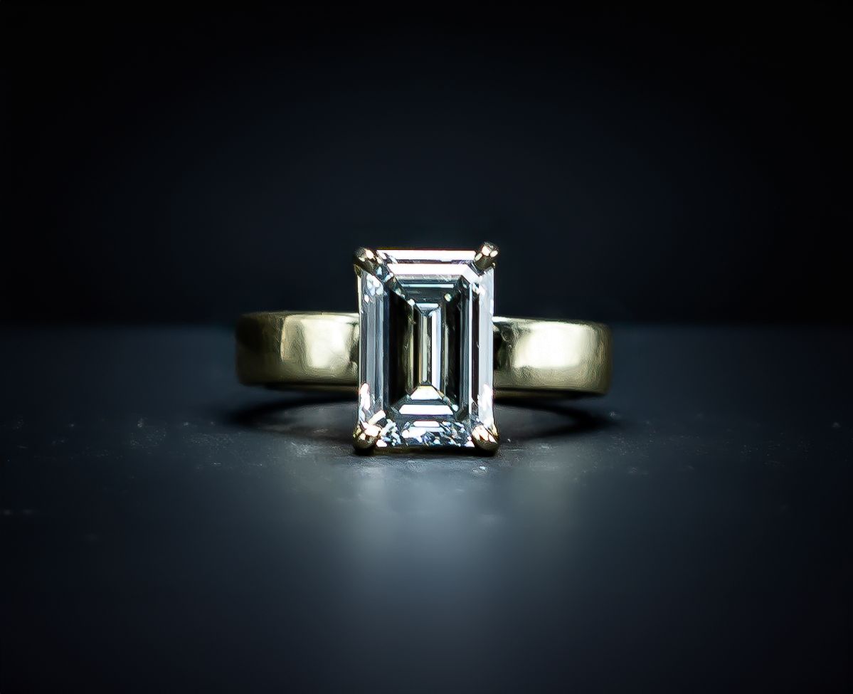 Emerald-cut diamond ring with a gold band on a dark background
