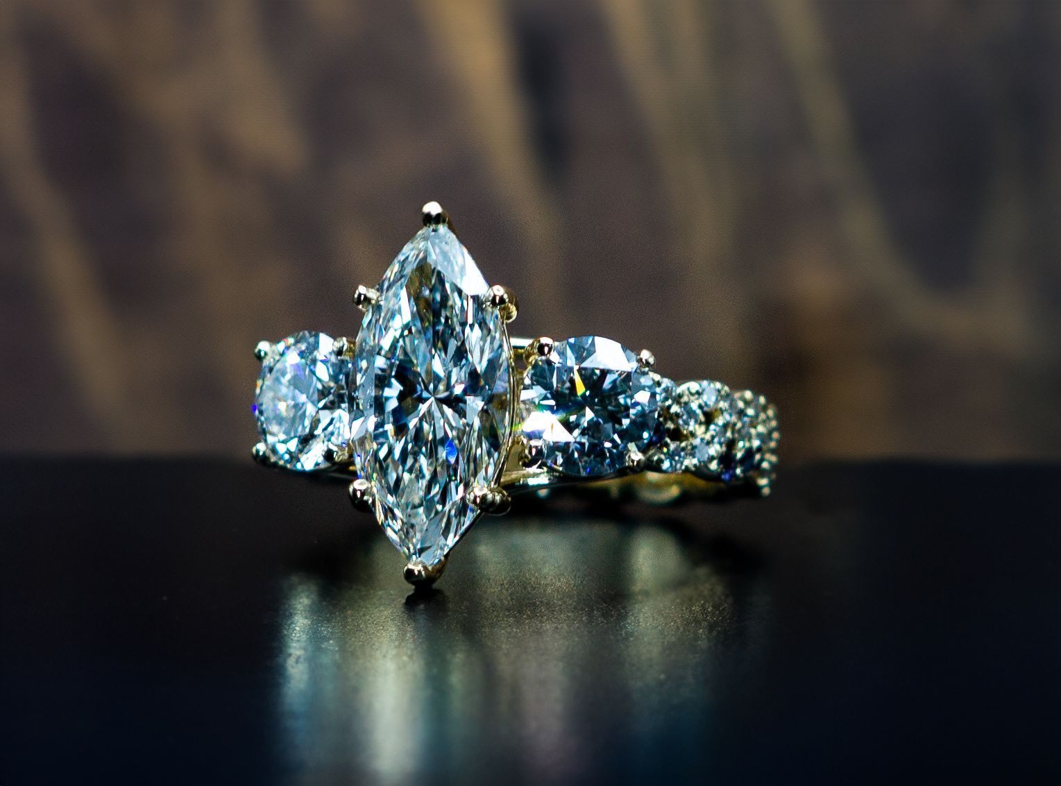 Diamonds on a ring with a large pear-shaped center stone and side stones on a dark reflective surface