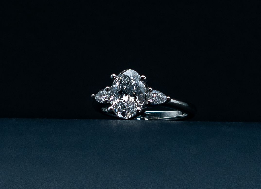 Diamond engagement ring on a dark blue surface against a black background.