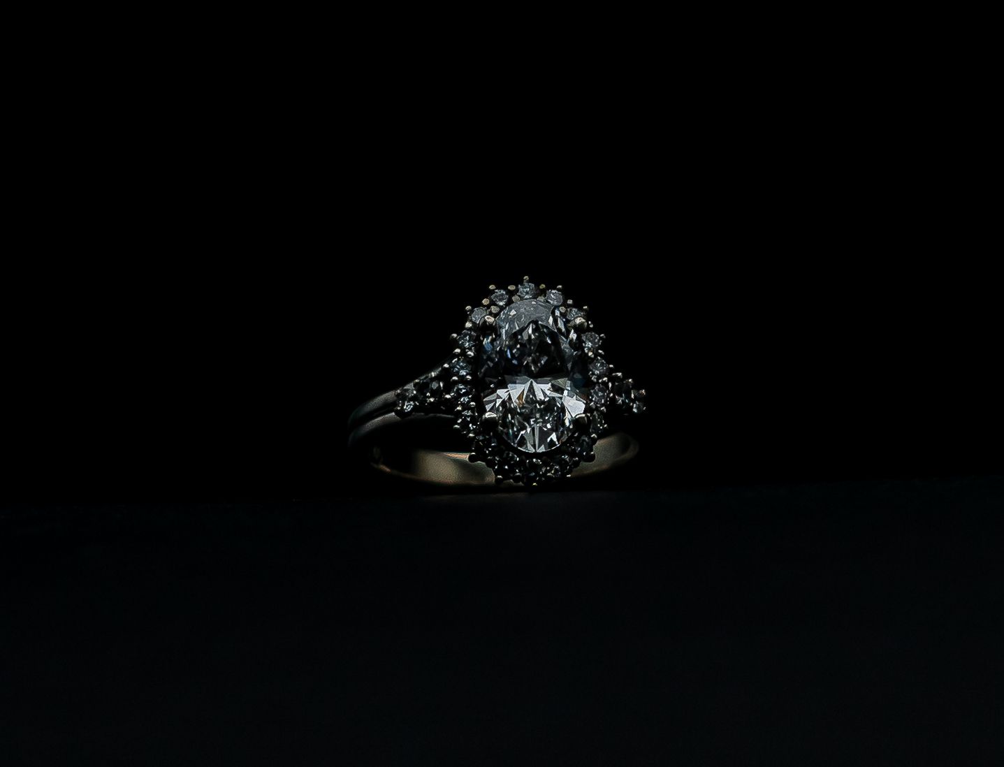 Diamond ring on a dark background, spotlighted with a sparkling cluster setting
