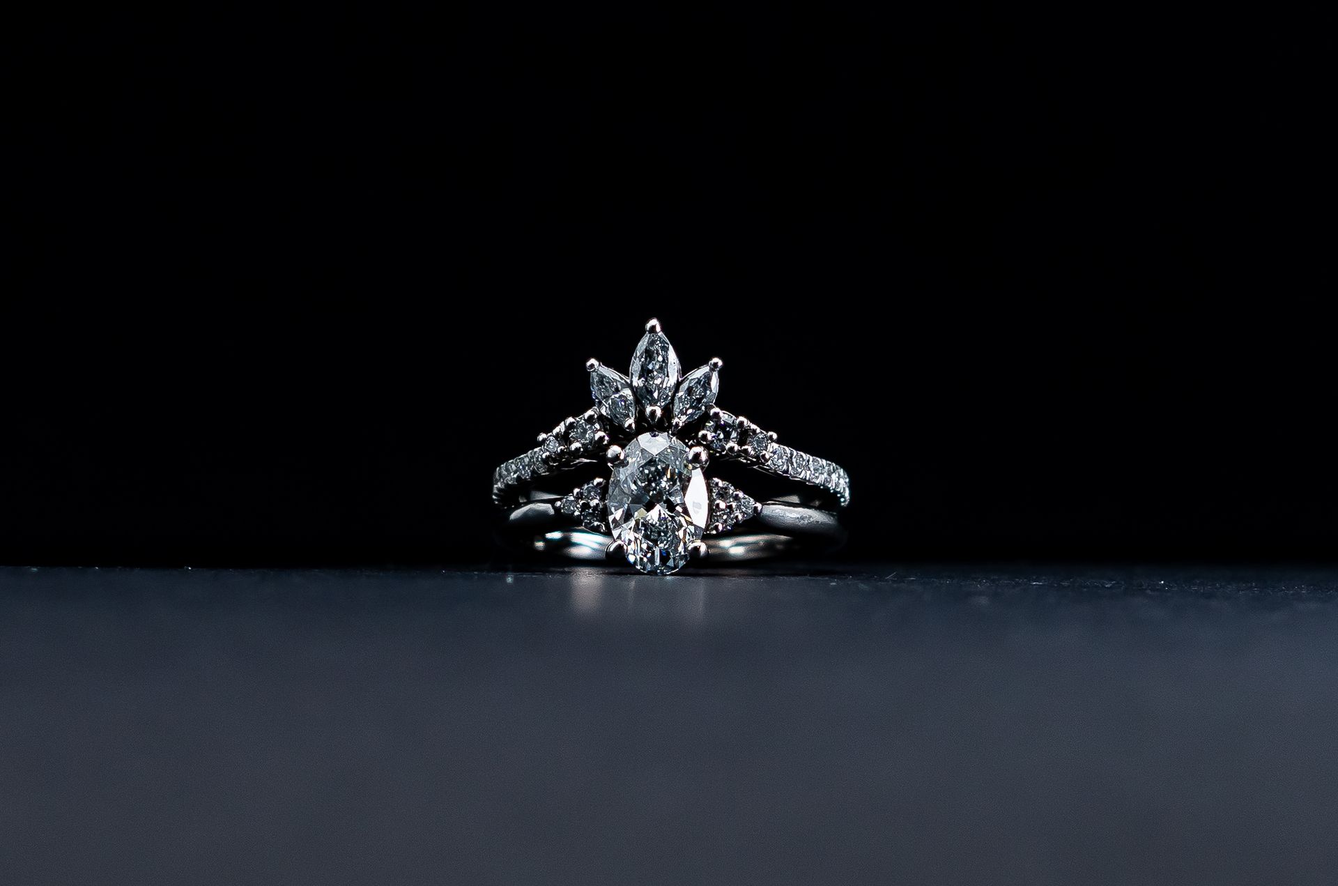 Silver floral diamond ring on a dark surface against a black background