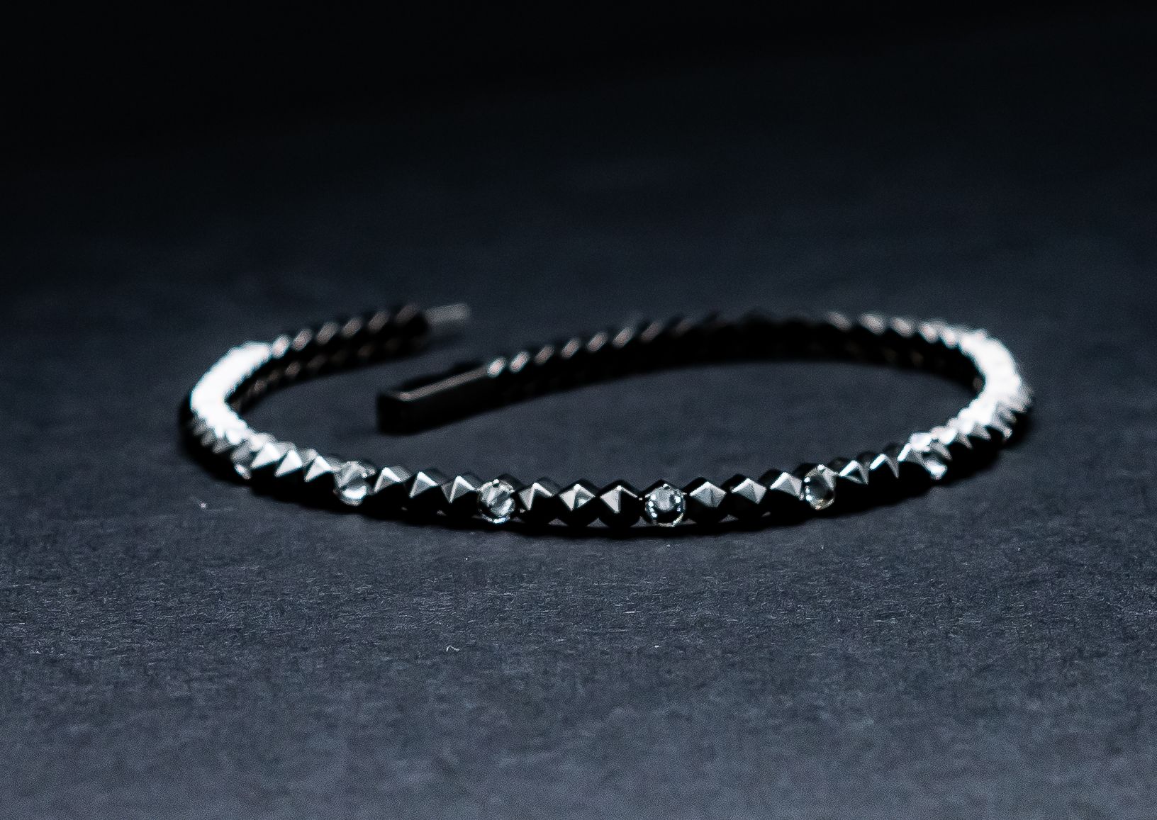 Black studded headband on a dark fabric background