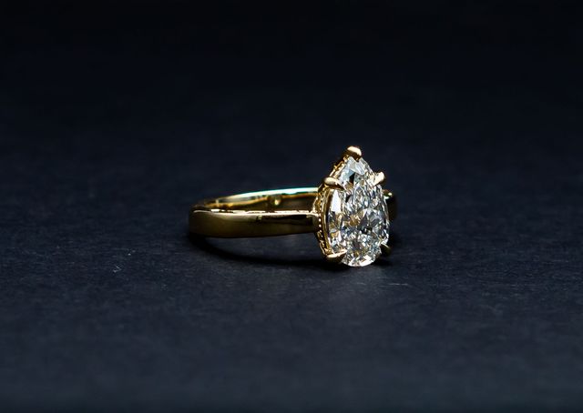 Gold pear-shaped diamond ring on a dark background