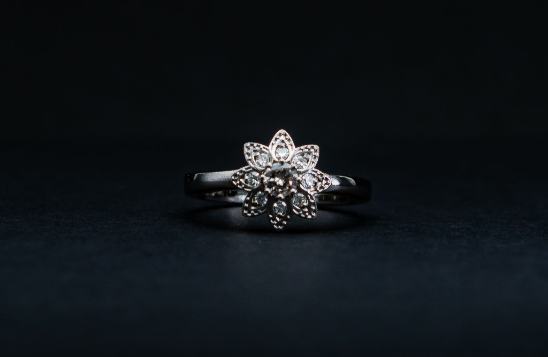 Silver floral diamond ring on a dark background