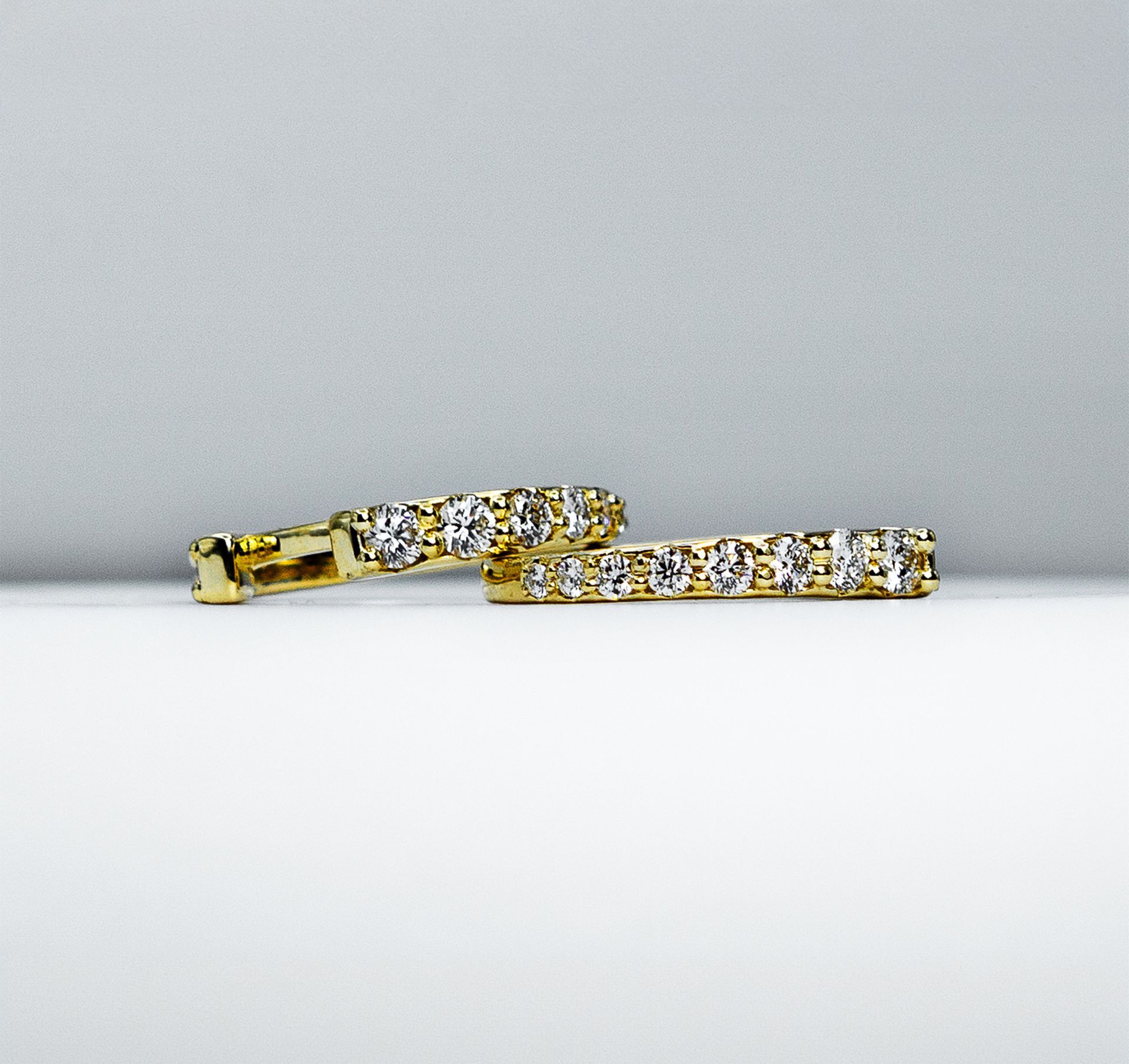 Gold bracelet with clear stones, shown on a light gray background.