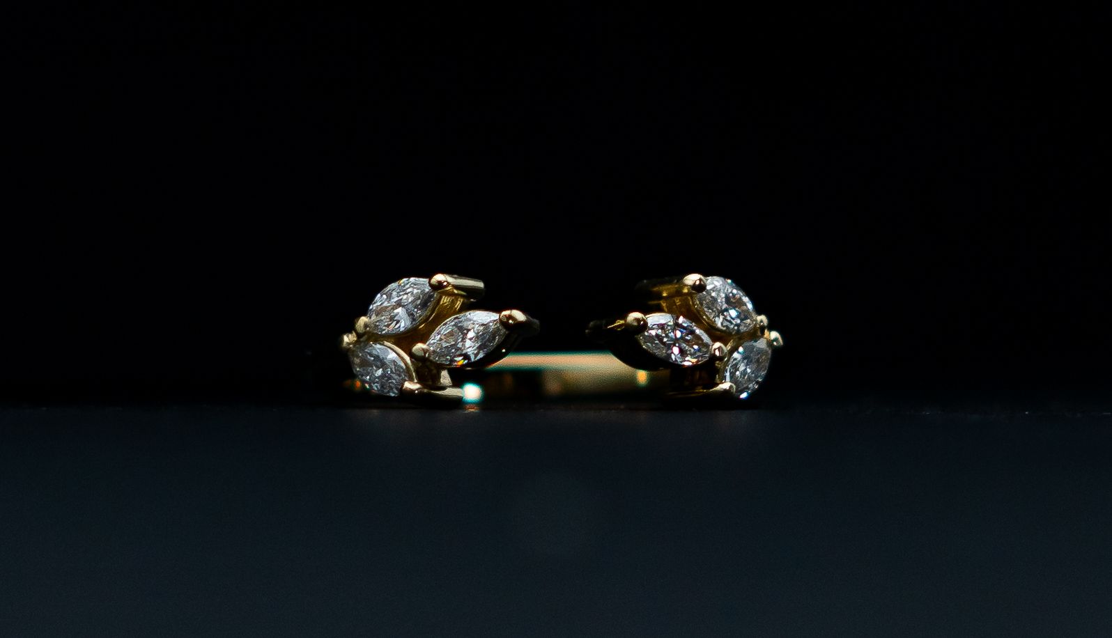 Pair of jeweled gold earrings on a dark background