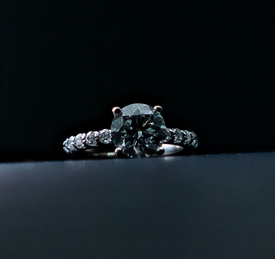 Diamond engagement ring on a dark surface with a black background