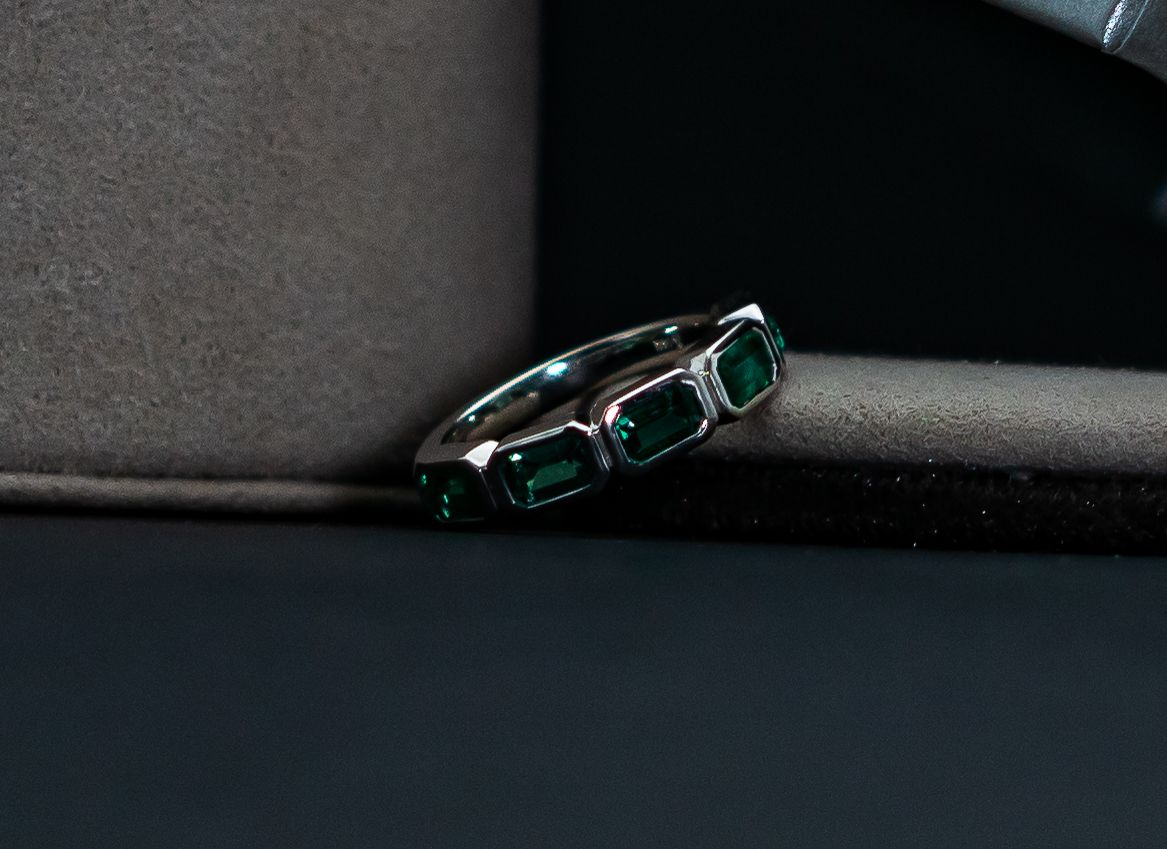 Green gemstone ring on a dark fabric surface, close-up.