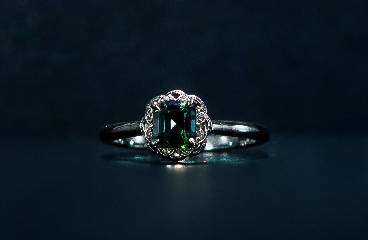 Silver ring with a dark green gemstone on a dark background