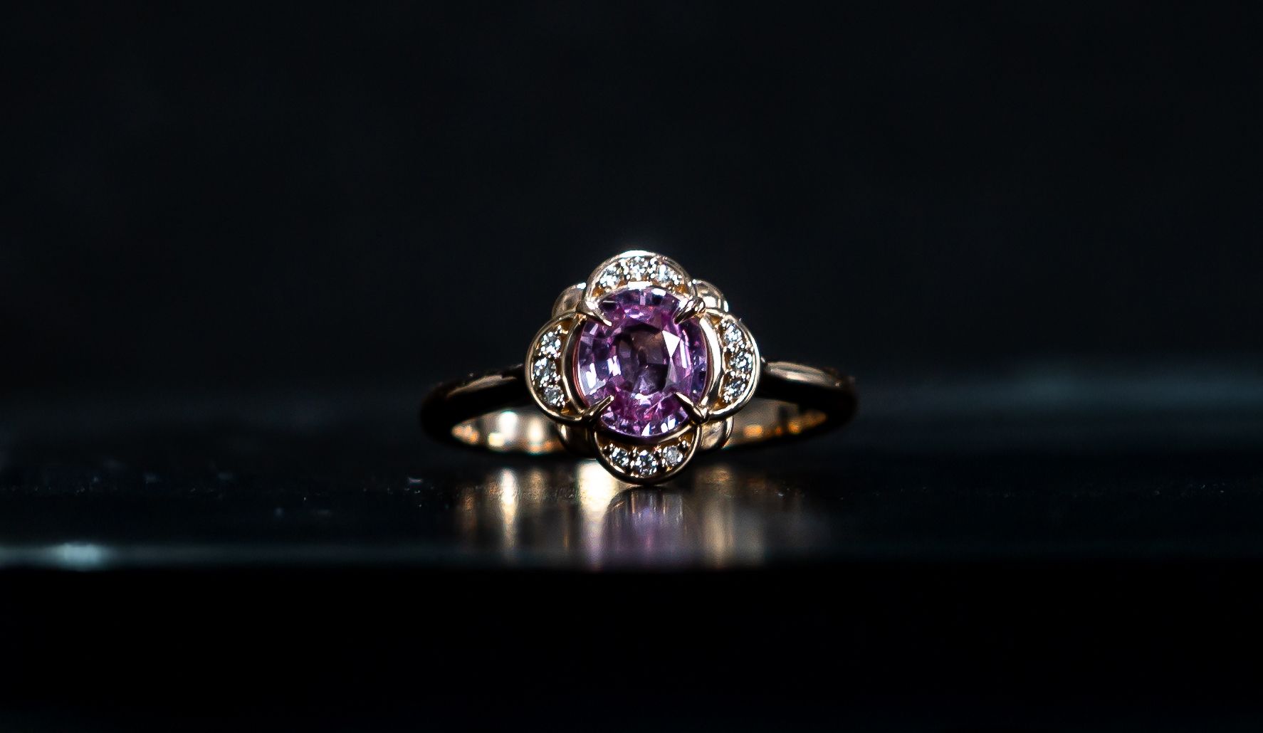 Gold ring with a purple gemstone on a dark reflective surface