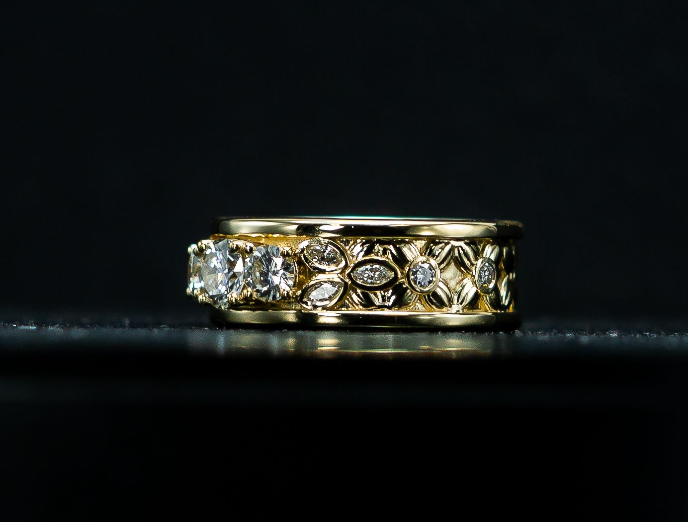 Gold and diamond ring on a black reflective surface