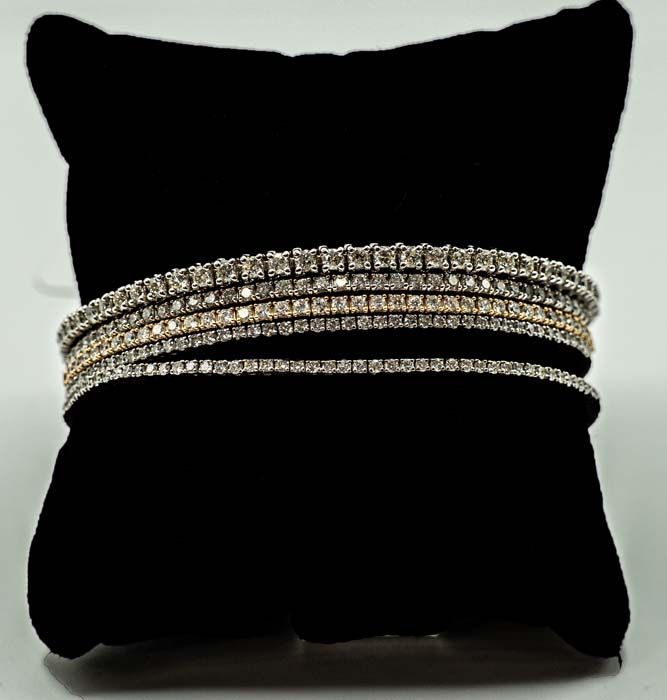 Black cushion displaying stacked silver and gold rhinestone bracelets